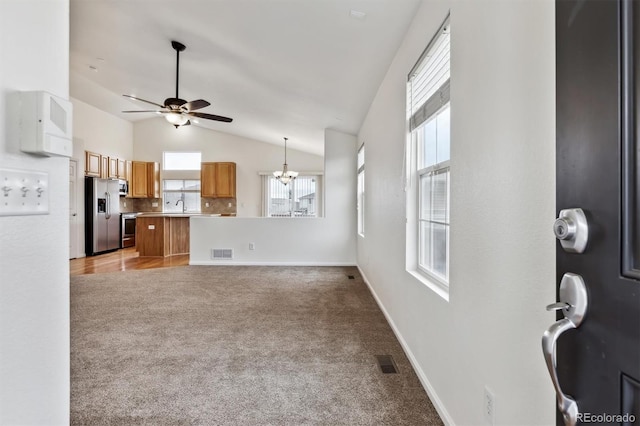 living room featuring baseboards, ceiling fan with notable chandelier, visible vents, and light colored carpet