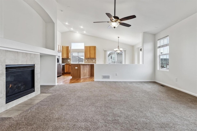 unfurnished living room with light colored carpet, visible vents, a tile fireplace, baseboards, and ceiling fan with notable chandelier