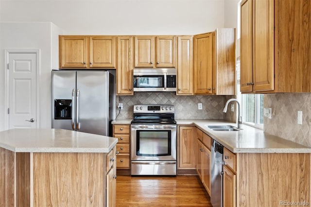 kitchen with appliances with stainless steel finishes, a center island, a sink, light wood-type flooring, and backsplash