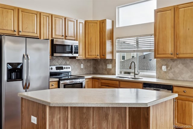 kitchen featuring light stone counters, stainless steel appliances, a sink, a center island, and tasteful backsplash