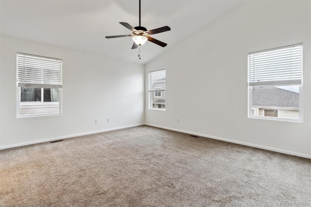 empty room with lofted ceiling, carpet floors, visible vents, a ceiling fan, and baseboards