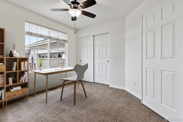 carpeted office space featuring ceiling fan and baseboards