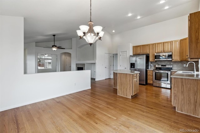 kitchen featuring a center island, light wood finished floors, stainless steel appliances, open floor plan, and a sink