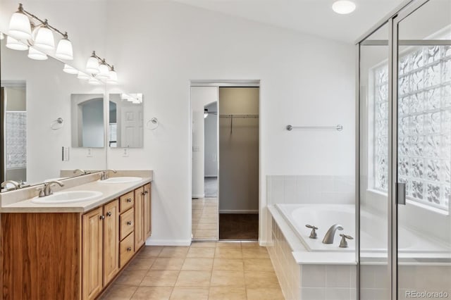 bathroom with double vanity, a garden tub, a sink, and tile patterned floors