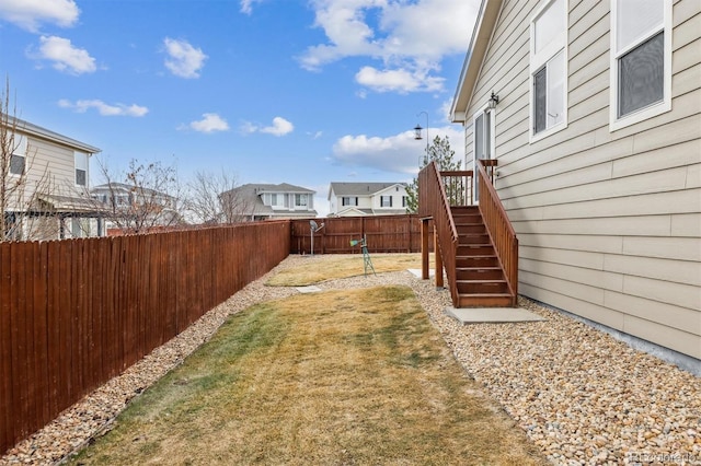 view of yard with stairs, a fenced backyard, and a residential view