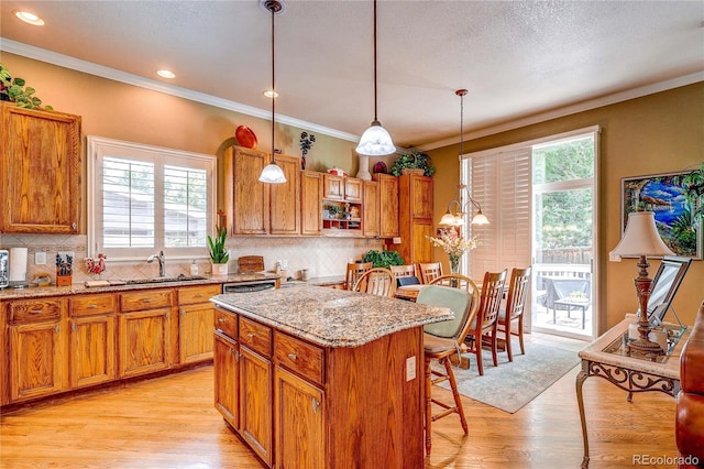 10292 Nickolas Ave, Highlands Ranch, CO 80130 - kitchen featuring healthy amount of natural light, brown cabinetry, light stone counters, crown molding, and recessed lighting