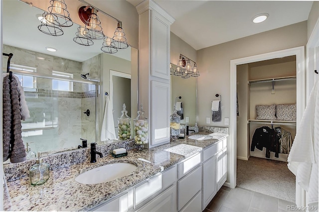 bathroom with tile patterned floors, a shower with door, an inviting chandelier, and vanity