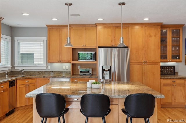 1526 S Gaylord St, Denver, CO 80210 - kitchen with stainless steel appliances, a sink, a center island, light wood-style floors, and a kitchen breakfast bar