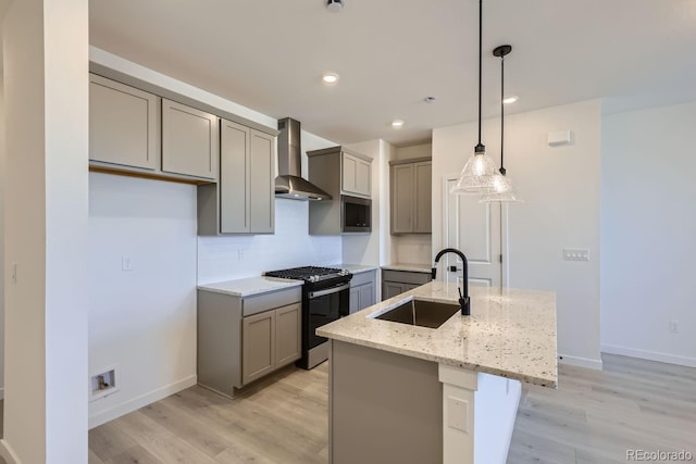 kitchen with pendant lighting, wall chimney exhaust hood, sink, a kitchen island with sink, and stainless steel range with gas stovetop