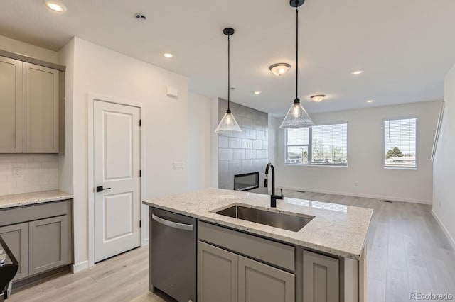 kitchen with dishwasher, gray cabinetry, sink, backsplash, and a center island with sink