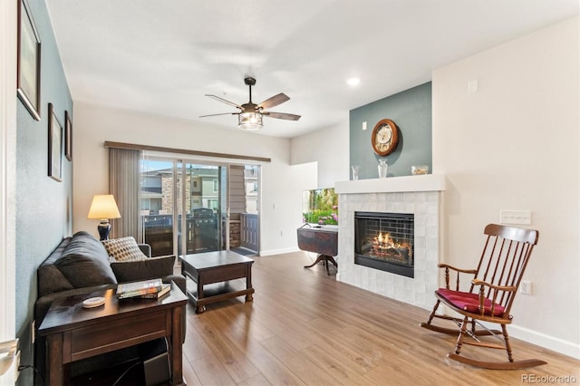 living room featuring a fireplace, wood-type flooring, and ceiling fan