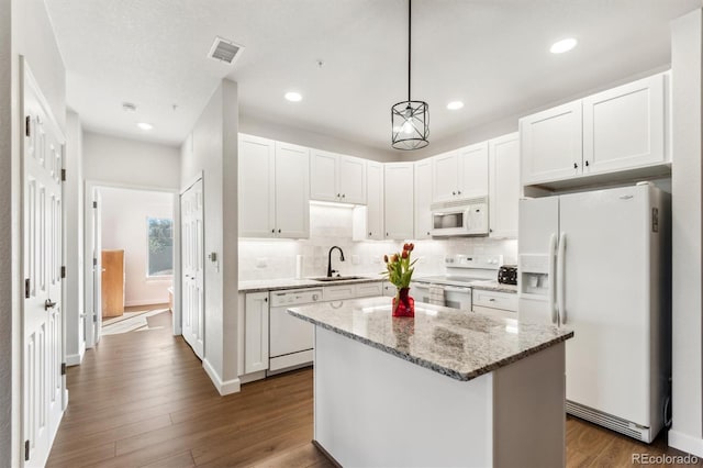 kitchen with sink, a kitchen island, pendant lighting, white appliances, and white cabinets