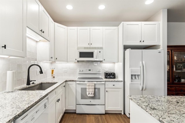 kitchen with sink, white appliances, white cabinetry, hardwood / wood-style floors, and tasteful backsplash