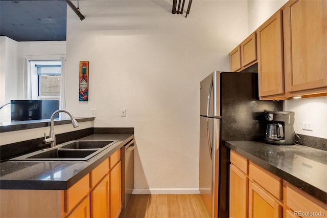 kitchen featuring dishwasher, sink, dark stone counters, and light hardwood / wood-style flooring