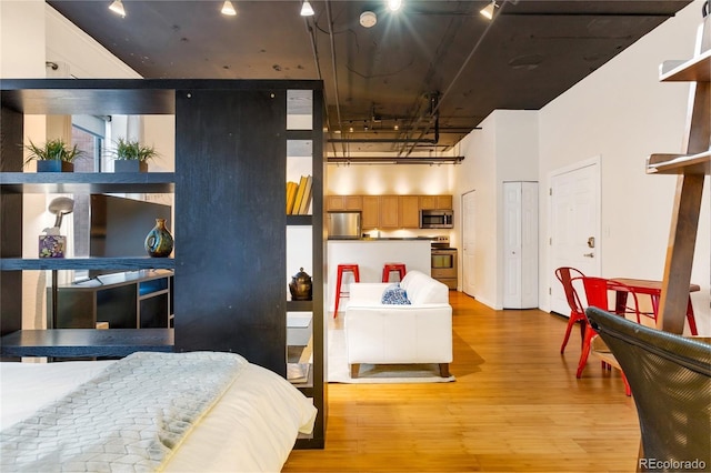 bedroom with two closets, stainless steel fridge, and light hardwood / wood-style flooring