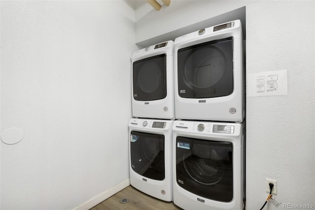 washroom with hardwood / wood-style floors and stacked washer and dryer