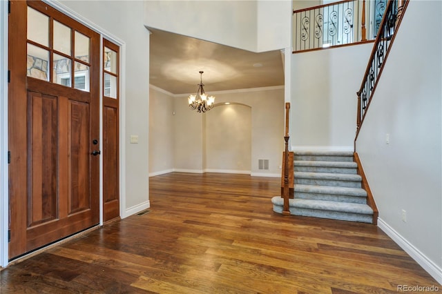 foyer entrance with visible vents, stairway, ornamental molding, wood finished floors, and baseboards