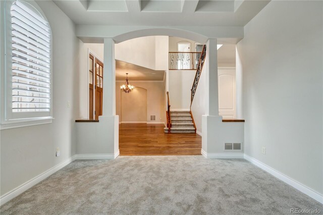 interior space with baseboards, visible vents, arched walkways, stairs, and a notable chandelier