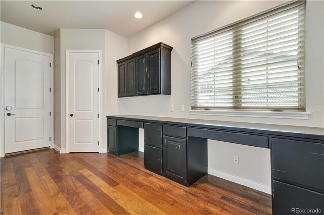 unfurnished office with dark wood-type flooring, recessed lighting, built in study area, and baseboards