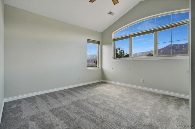 carpeted spare room with lofted ceiling, visible vents, ceiling fan, a mountain view, and baseboards