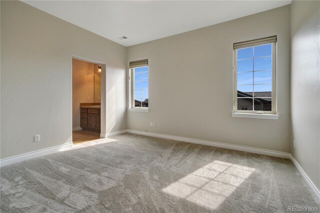 unfurnished bedroom featuring carpet floors, connected bathroom, visible vents, and baseboards