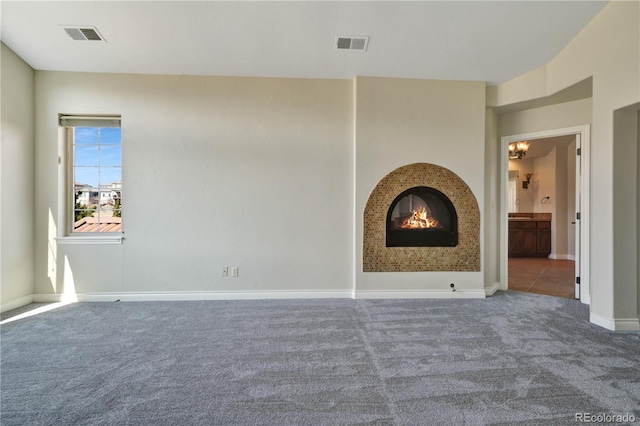 unfurnished living room featuring carpet, visible vents, baseboards, and a lit fireplace