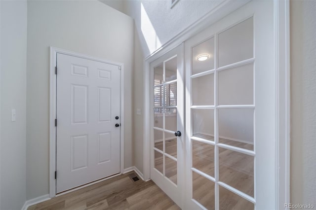 entryway with baseboards, french doors, and wood finished floors
