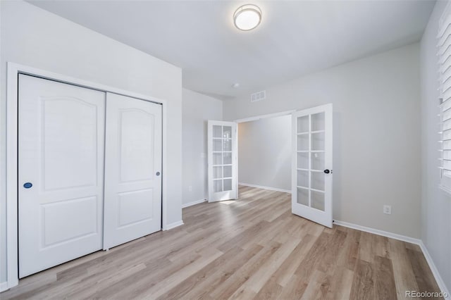 unfurnished bedroom featuring visible vents, a closet, baseboards, french doors, and light wood-style flooring