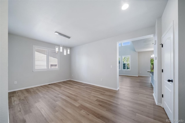 empty room featuring baseboards, wood finished floors, and an inviting chandelier