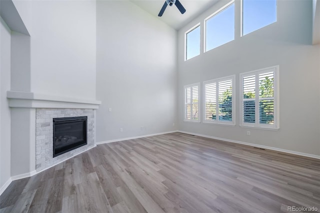 unfurnished living room featuring high vaulted ceiling, plenty of natural light, ceiling fan, and wood finished floors