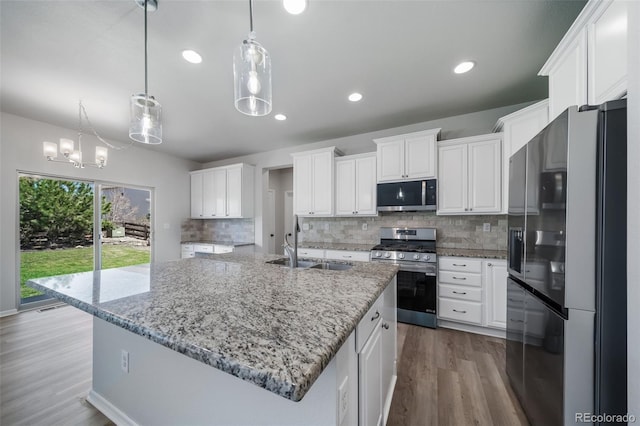 kitchen with white cabinets, appliances with stainless steel finishes, a sink, tasteful backsplash, and dark wood-style floors