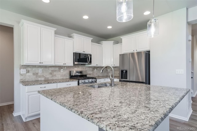 kitchen with a sink, white cabinetry, appliances with stainless steel finishes, and wood finished floors