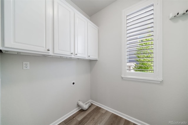 washroom featuring baseboards, hookup for an electric dryer, cabinet space, and wood finished floors