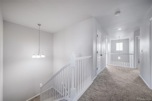 corridor with an inviting chandelier, carpet, and an upstairs landing