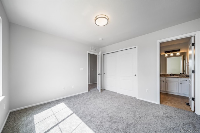 unfurnished bedroom with visible vents, a closet, baseboards, a sink, and carpet