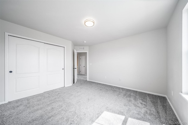 unfurnished bedroom featuring carpet flooring, baseboards, visible vents, and a closet