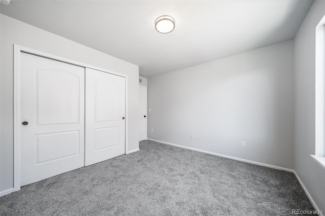 unfurnished bedroom featuring baseboards, carpet flooring, and a closet