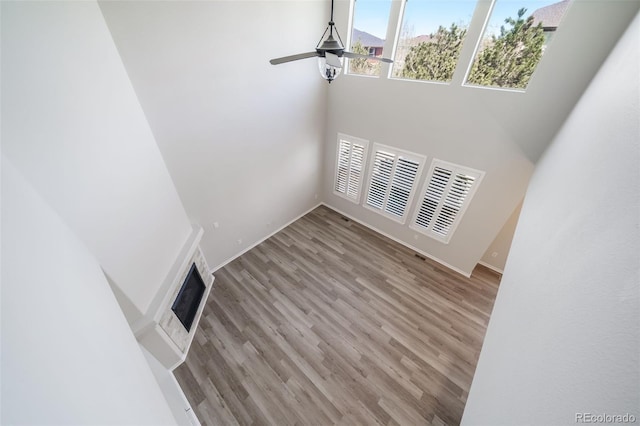 unfurnished living room featuring baseboards, a high ceiling, wood finished floors, and visible vents