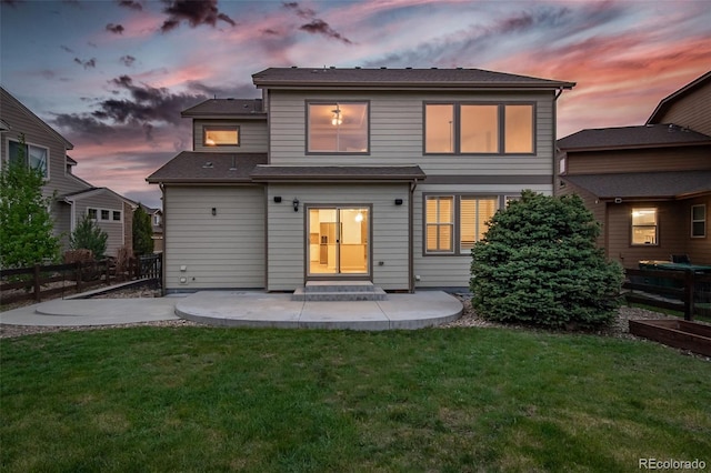 back of property at dusk with a patio area, fence, a yard, and entry steps