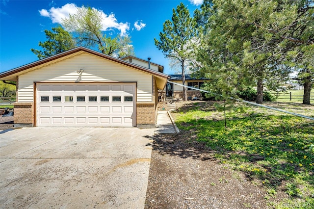 view of front of home with brick siding, a garage, concrete driveway, and fence