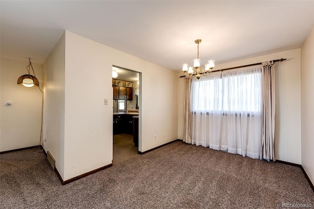 carpeted empty room featuring a chandelier and baseboards