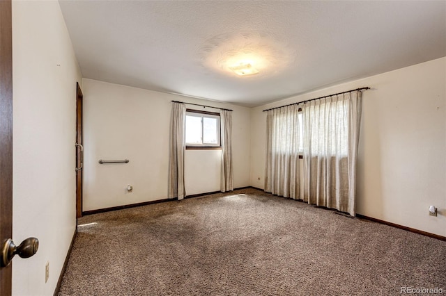 unfurnished room featuring carpet and baseboards