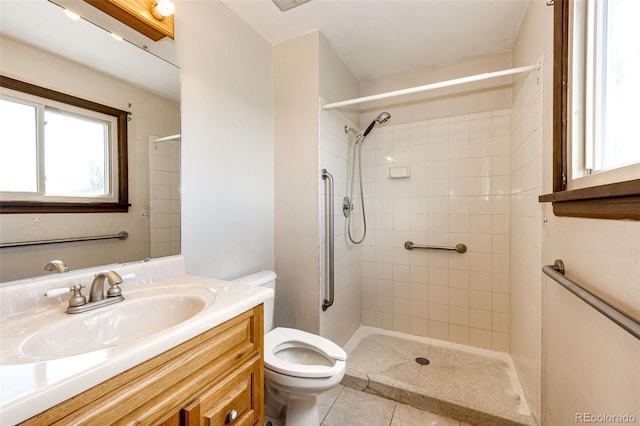 full bathroom with toilet, vanity, a tile shower, and tile patterned flooring