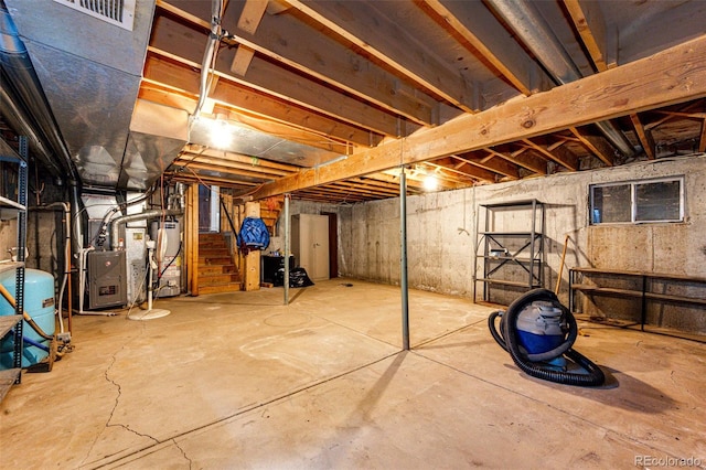 unfinished below grade area with a water pressure tank, heating unit, stairway, and water heater