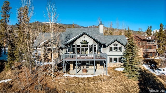 rear view of house with a patio and a deck with mountain view