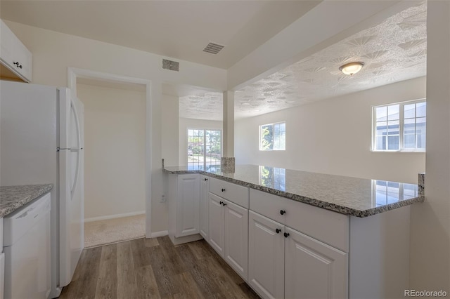 967 Victor St, Aurora, CO 80011 - kitchen with white appliances, dark wood-style flooring, a peninsula, white cabinetry, and light stone counters