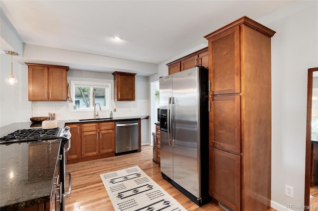 3175 S Pennsylvania St, Englewood, CO 80113 - kitchen featuring appliances with stainless steel finishes, light wood-style floors, a sink, decorative backsplash, and dark stone countertops