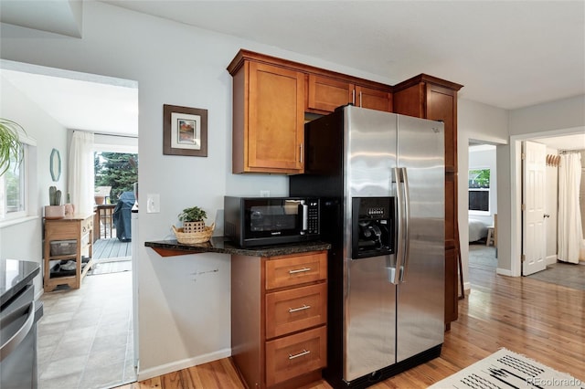 3175 S Pennsylvania St, Englewood, CO 80113 - kitchen featuring stainless steel appliances, brown cabinetry, light wood-type flooring, and dark stone countertops