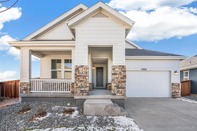 craftsman-style home featuring driveway, roof with shingles, covered porch, stone siding, and a garage