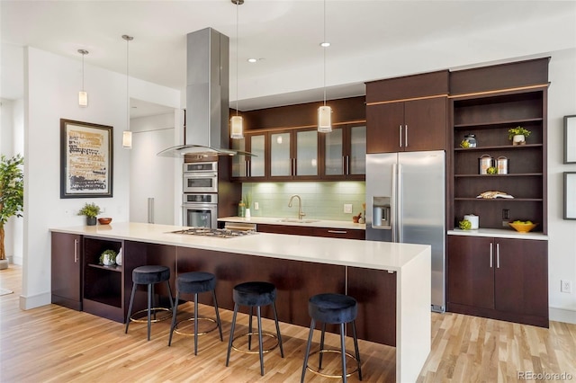 kitchen featuring island exhaust hood, a kitchen bar, hanging light fixtures, and kitchen peninsula